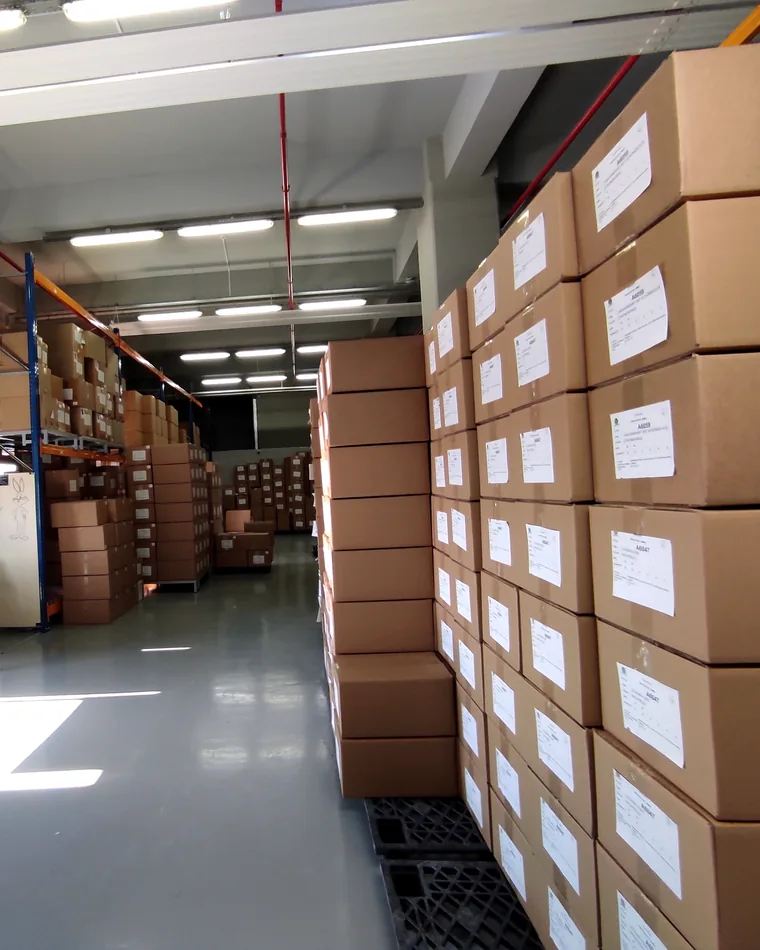 Cartons of finished garments on pallets, each labelled with its order number.
